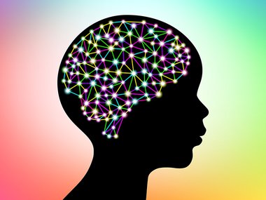 Side portrait of a child's face ontop of a rainbow background with different interconntected dots in the shape of a brain.