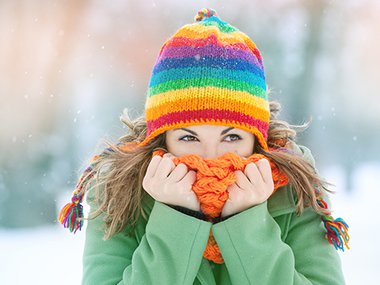Women in the snow with scarf around her face.
