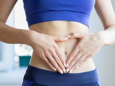 Women standing with hands on her stomach in a triangle shape