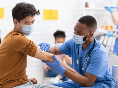 Male medical professional giving another man a vaccine at a vaccination clinic