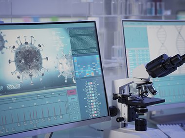 Research on computer monitors and a microscope between them.