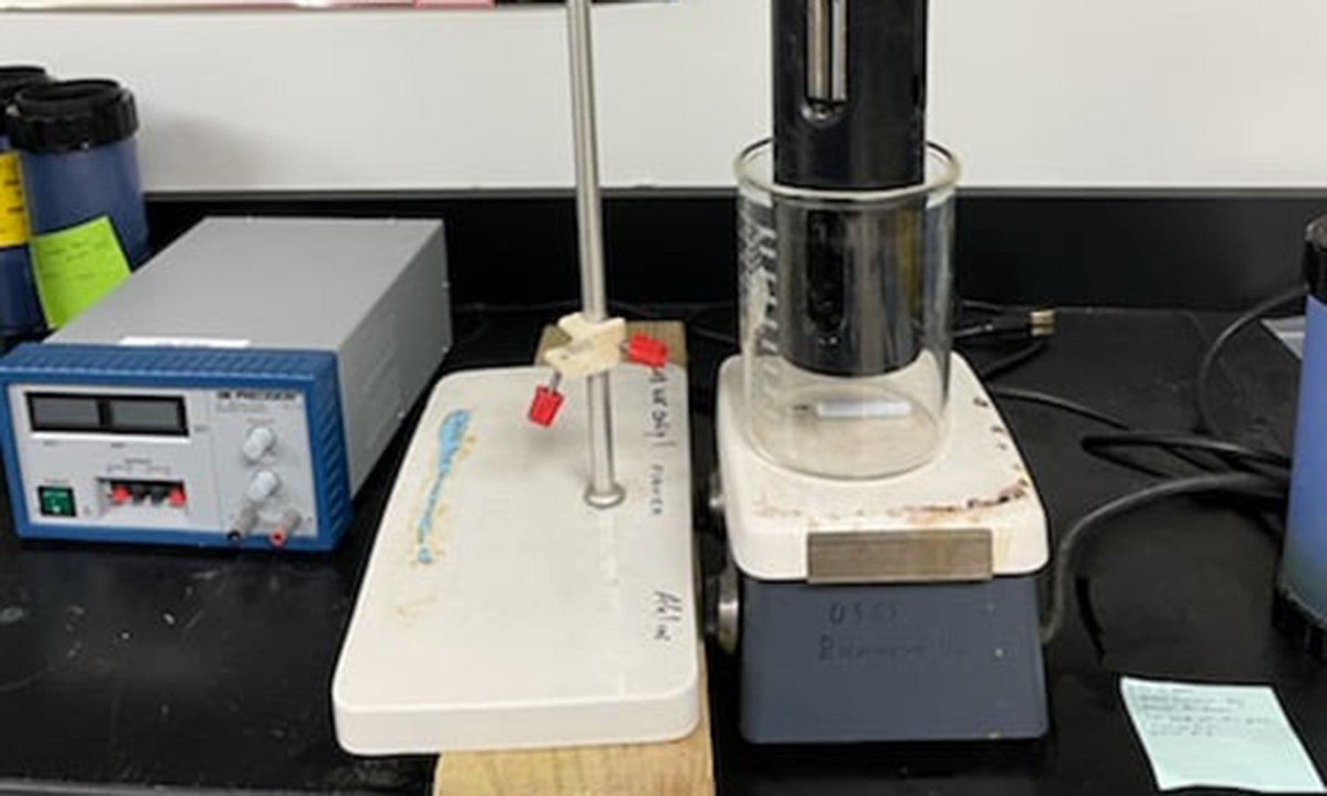 Lab equipment, including a beaker, scale, and other equipment on a black table.