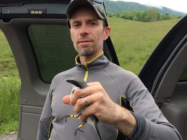 Ornithologist Sergio Harding holds a bird he banded during field work.