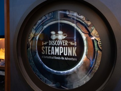 A photograph of a decorative sign at the Virginia Aquarium for the Discover Steampunk exhibit. The sign reads "Discover Steampunk: A Fantastical Hands-On Adventure