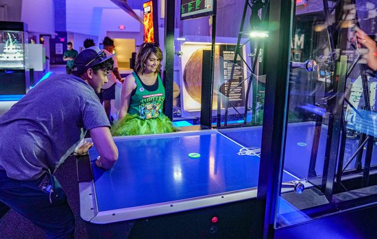 Adult battles air hockey robot in Speed during Science on Tap event