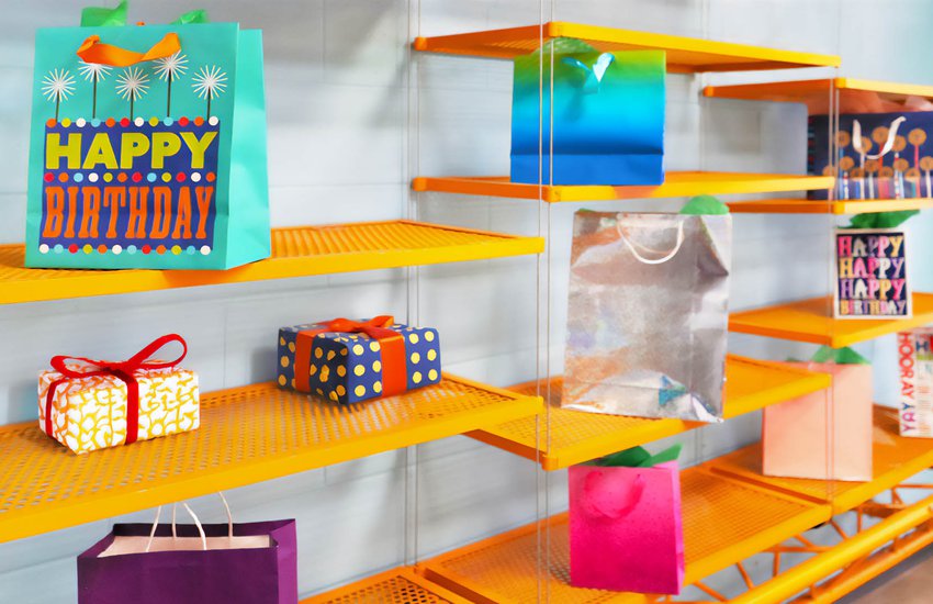 Birthday gifts in bright colored bags sitting on a vivid orange shelf in the Challenge Lab.jpg