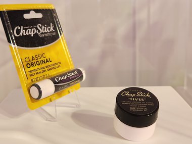 A photo of a tube of Chapstick in its original package and a small round container of lip balm sitting to its right.