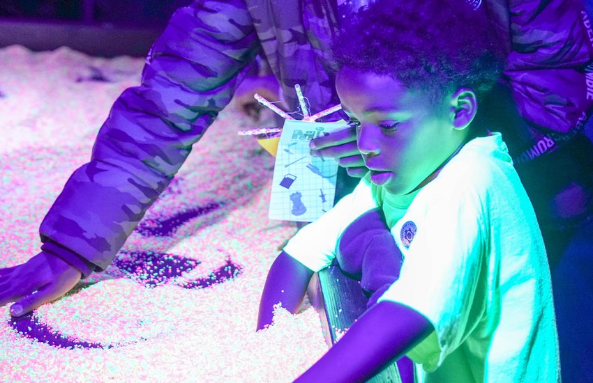 Child enjoying black light activities at the Glow event