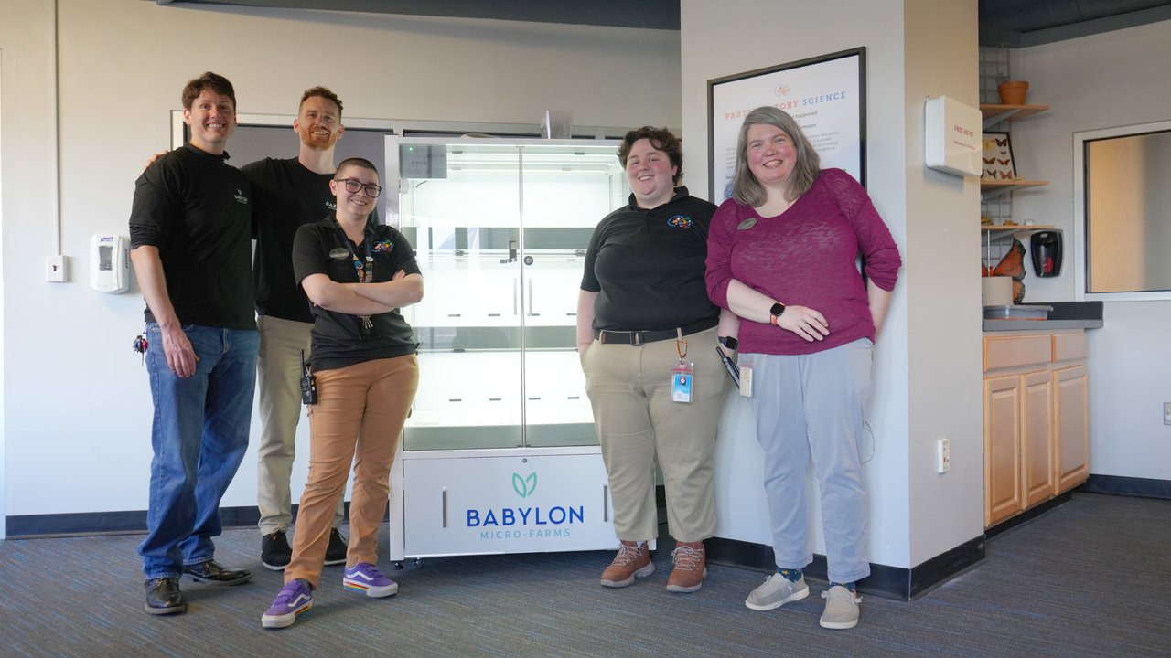 Group of people posing in front of a hydroponic vertical farming unit from Babylon Micro-Farms.jpg