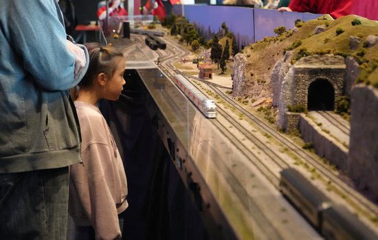 child overlooking model railroad train with parent .jpg
