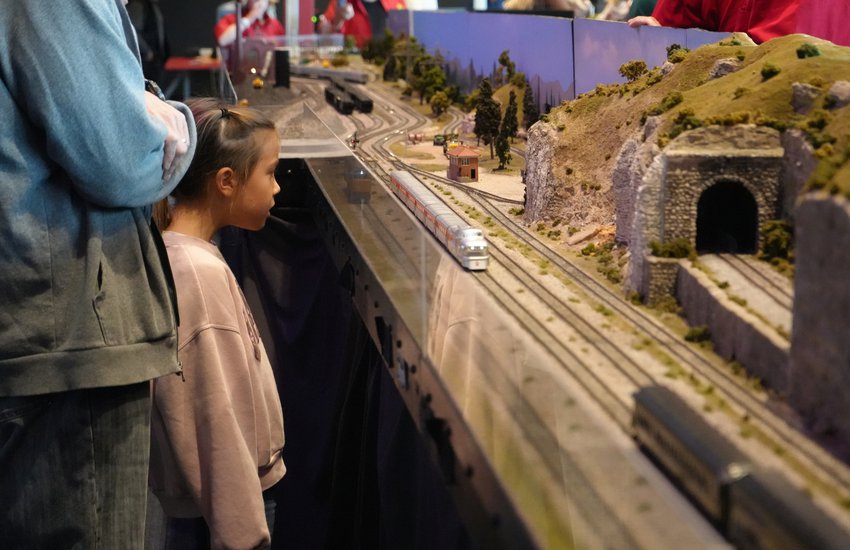 child overlooking model railroad train with parent .jpg