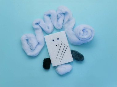 decorative image of a piece of felt depicting a face with hair