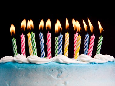 Decorative birthday cake with multi-colored lit candles