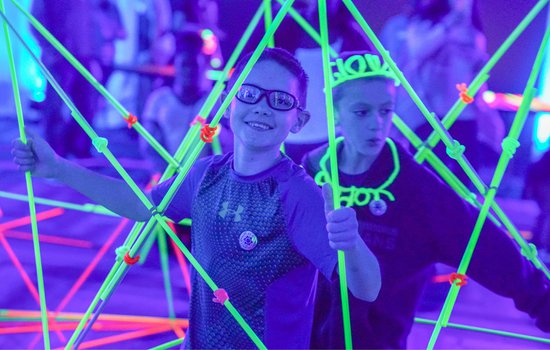 Image of kids having fun with building materials and black lights for the event Glow