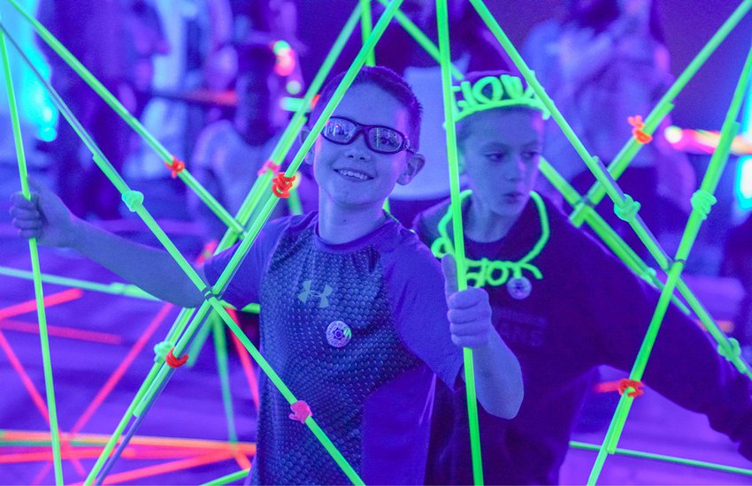 Image of kids having fun with building materials and black lights for the event Glow
