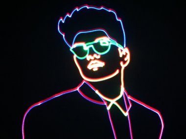 An outline of a singer and songwriter, Bruno Mars, created with colorful neon lasers