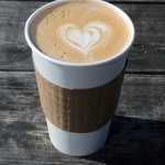 latte in a paper cup with a heart