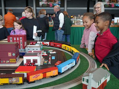 adults and children surround and admire a display of model city and trains.jpg