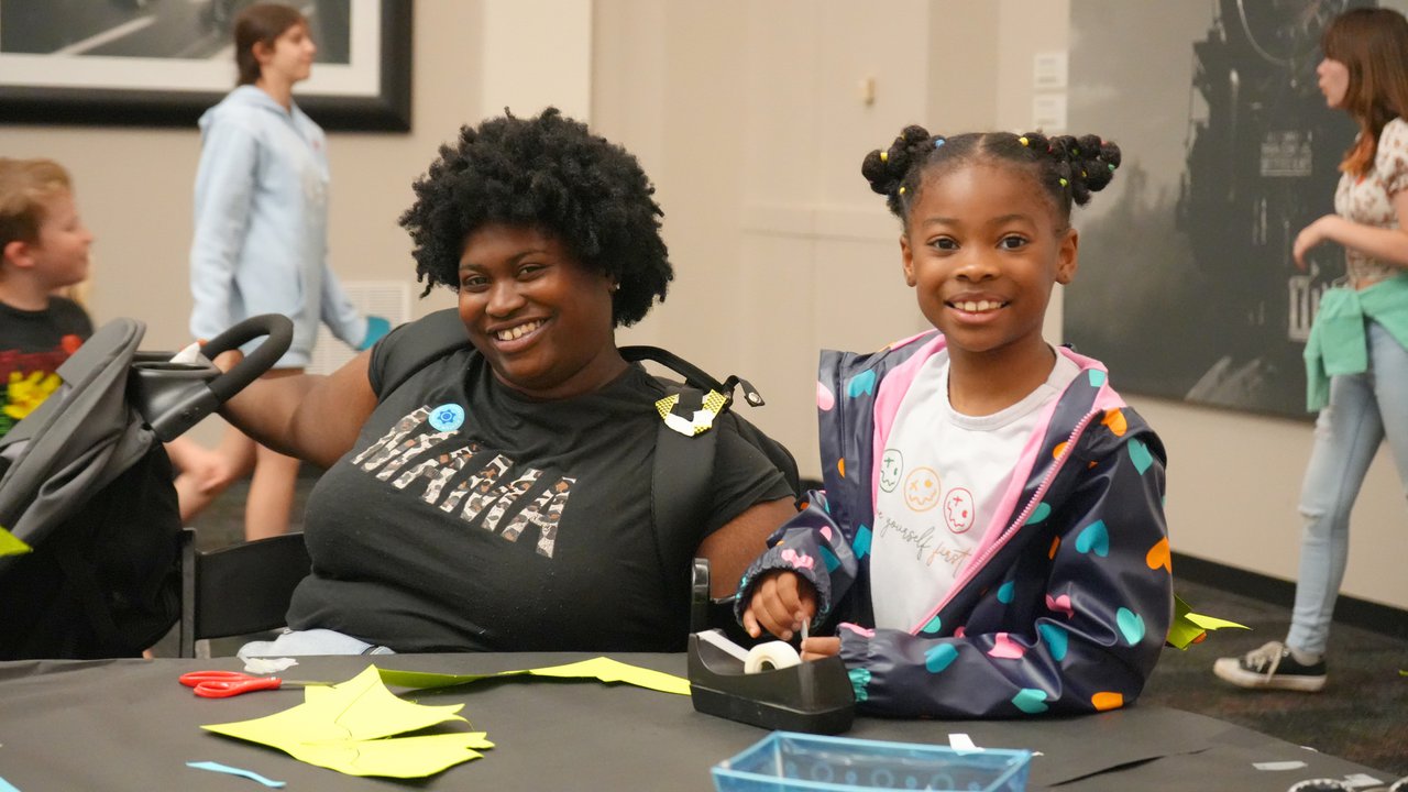 Mother and Daugther sitting side by side at a table smiling at the camera .jpg