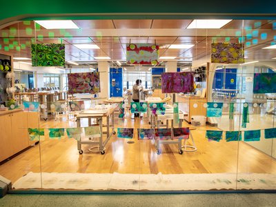 Colorful artwork displayed on a glass window. The Forge workshop can also be seen through the window.