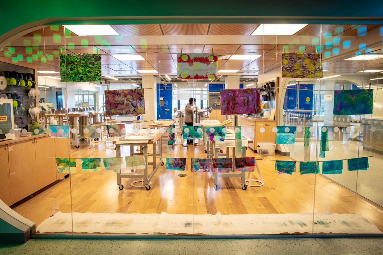 Colorful artwork displayed on a glass window. The Forge workshop can also be seen through the window.