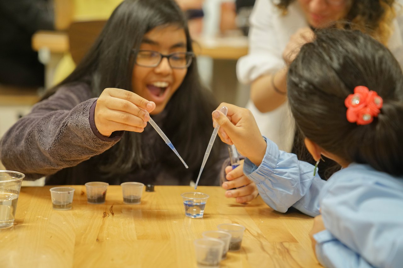 Girls performing and experiment with water. and pipets.