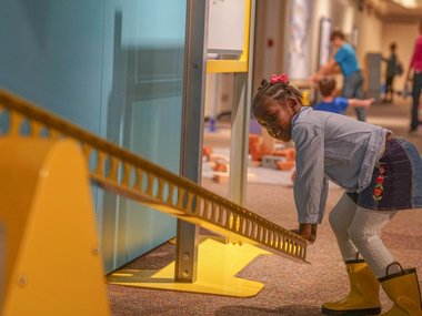 young girl exerting force on a balance beam in the Science Unplugged exhibit