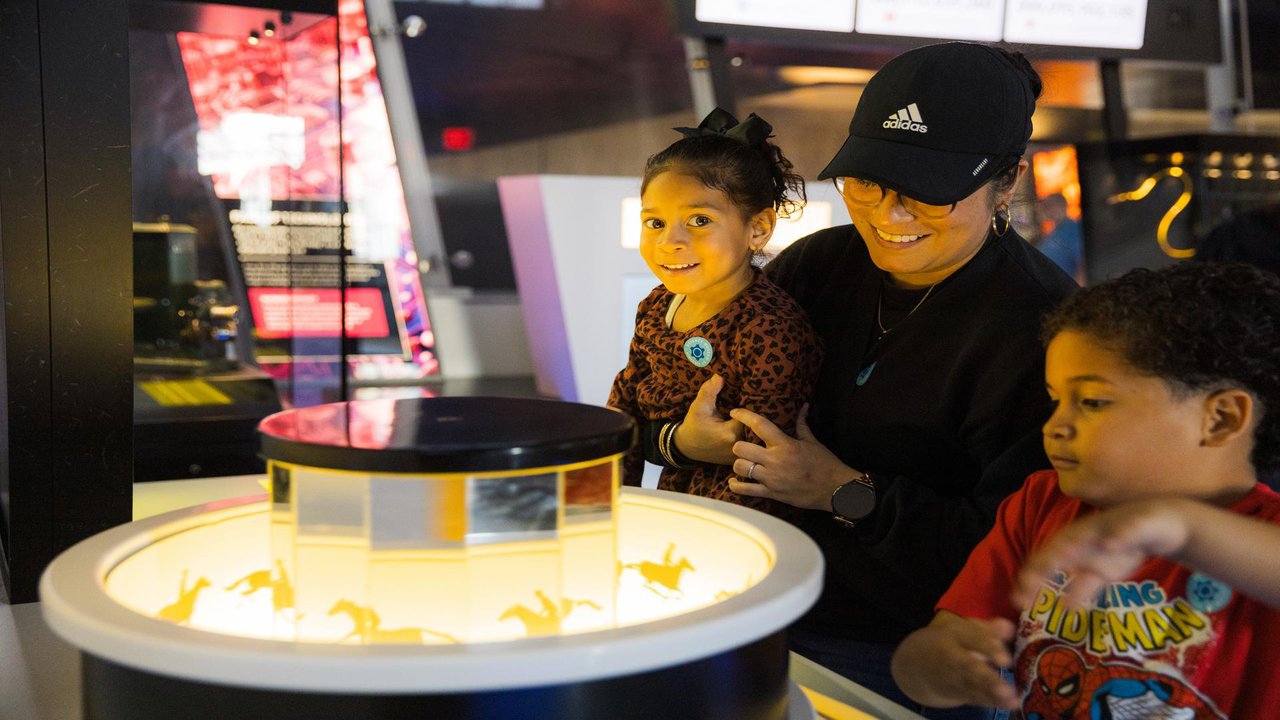 adult female holding child overlooking an exhibit with second child standing nearby.jpg