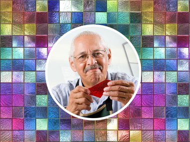 Male Senior holding a piece of stained glass surrounded by a staind glass backgroun.jpg