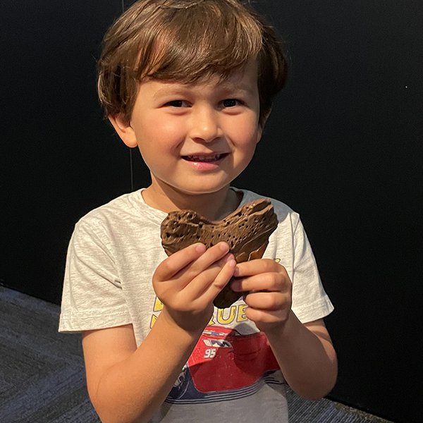 Little boy holding a shark tooth fossil.
