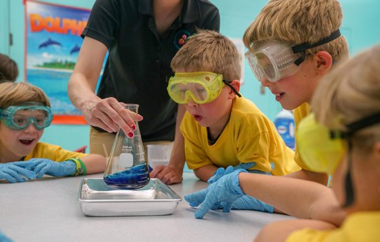 Summer campers watching a science experience with safety goggles on.
