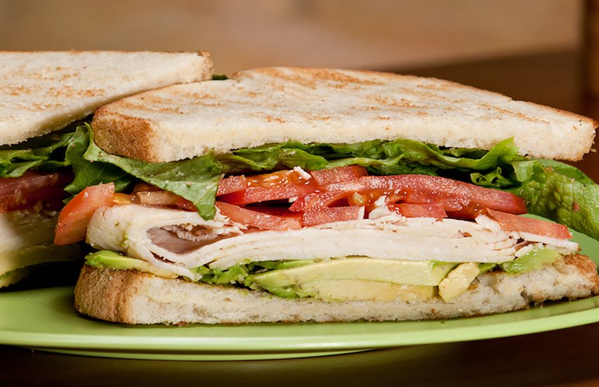 half of a turkey sandwich with lettuce and tomato