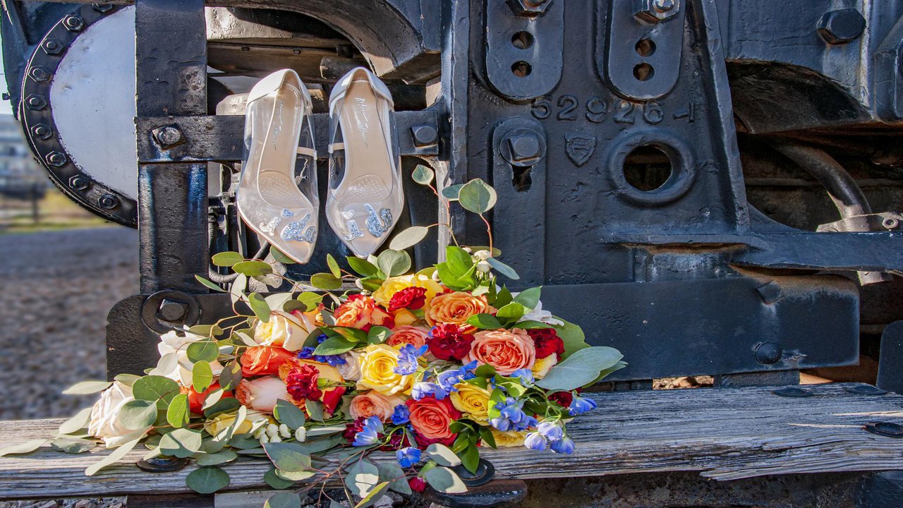 colorful bouquet of flowers belonging to a bride and their shoes perched on a train.jpg