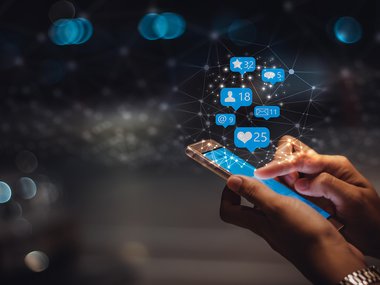 decorative image holding a mobile one with bubbles of social media reactionsjpg