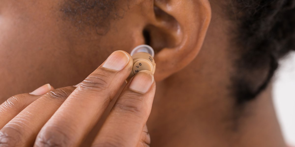 Woman placing a hearing aid in her ear