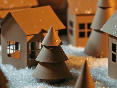 An image of a miniature cardboard town with cardboard trees and artificial snow.