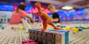 orange dinosaur figurine sits on top of lego piece.jpg