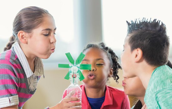 Children blowing on a wind turbine they created.