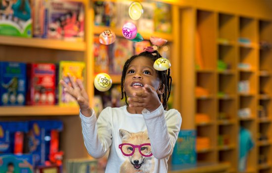 Girl tossing poppers with Science Museum wondermark on them in the air.