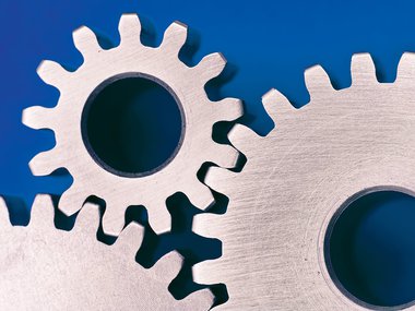 Wooden gears turning on a blue background.