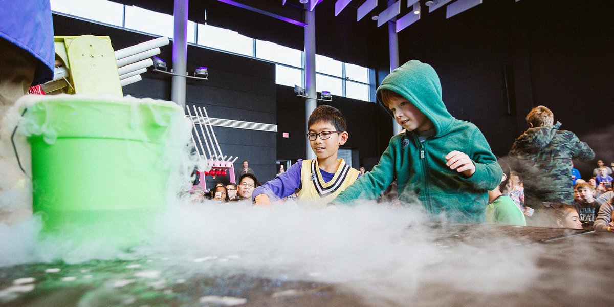 Children watching the supercool demo with awe as liquid nitrogen escapes from a green bucket.