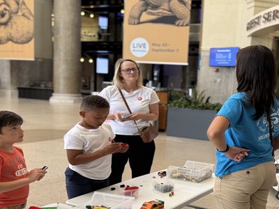 Teen volunteer stands behind a table while engaging with guests