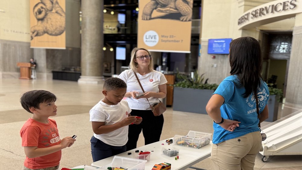 Teen volunteer stands behind a table while engaging with guests