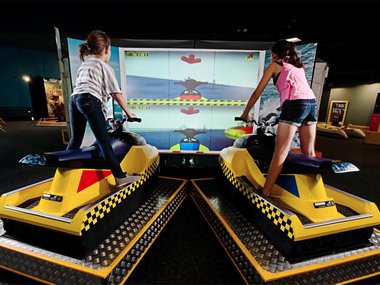 two girls standing up on interactive jet ski game.jpg